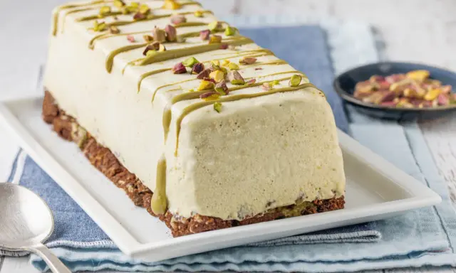 Semifreddo al pistacchio, un dolce gelato decorato con glassa verde e granella di pistacchi, su una base croccante.