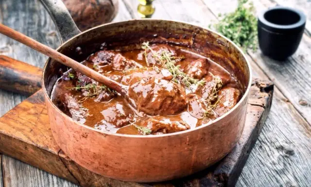 Un saporito brasato di manzo, cotto lentamente in una pentola di rame, guarnito con timo fresco.