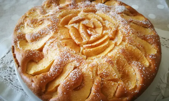 Una deliziosa torta di mele senza glutine, decorata con mele a forma di rosa e spolverata di zucchero a velo.