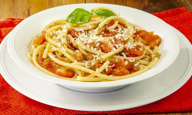 Un piatto invitante di pasta alla carrettiera, con pomodoro fresco, basilico e abbondante formaggio grattugiato.
