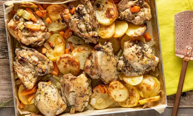 Sovracosce di pollo dorate al forno con patate, carote e sedano, pronte per essere servite.