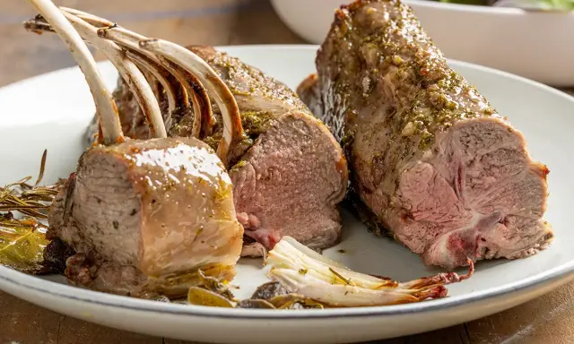 Costolette di agnello al forno succulente, condite con erbe aromatiche, servite su un piatto con verdure arrosto.