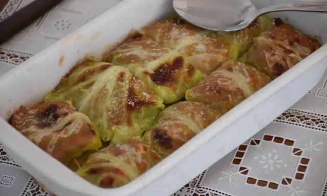 Involtini di verza con carne appena sfornati, dorati e spolverati di parmigiano, pronti per essere gustati.