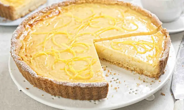 Una deliziosa crostata con crema pasticcera, guarnita con scorza di limone e spolverata di zucchero a velo.