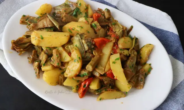 Deliziosi carciofi e patate in padella, un contorno saporito e colorato, arricchito da pomodorini e prezzemolo fresco.
