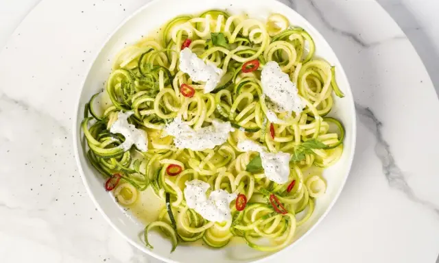 Spaghetti di zucchine freschi con ricotta cremosa, peperoncino e menta, un piatto leggero e colorato.