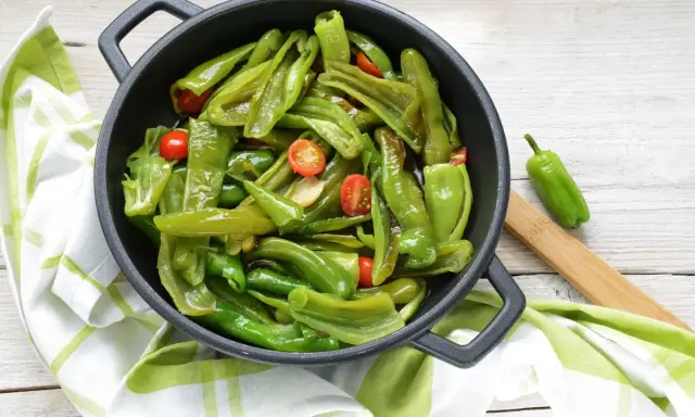 Friggitelli in padella, saltati con pomodorini e aglio, pronti per essere gustati.