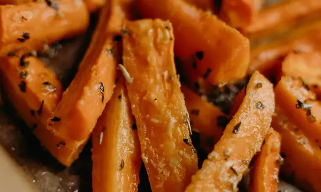 Carote in padella, tagliate a bastoncino e condite con erbe aromatiche, pronte per essere gustate.