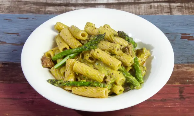 Piatto di pasta con asparagi e salsiccia, condita con una cremosa salsa verde.