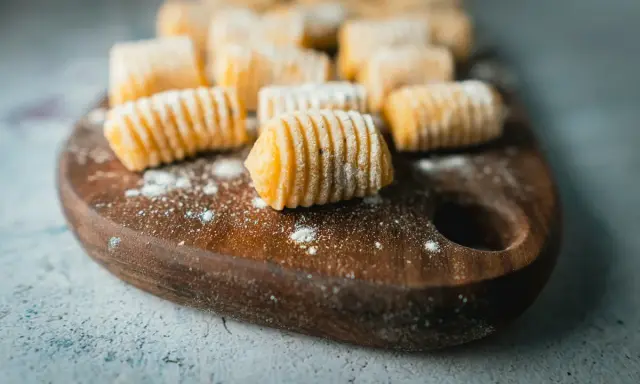 Gnocchi di patate fatti in casa, pronti per essere cucinati, spolverati di farina su un tagliere di legno.