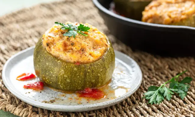 Zucchine ripiene in padella, un piatto gustoso e colorato, guarnito con prezzemolo fresco e servito su un piatto rustico.