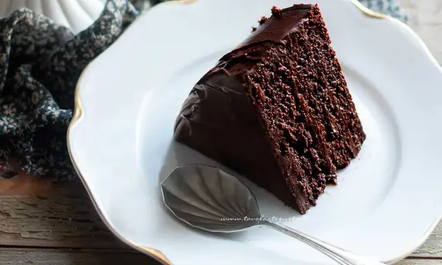 Una fetta di ciambellone al cioccolato, soffice e golosa, su un piatto bianco con un cucchiaino d'argento.