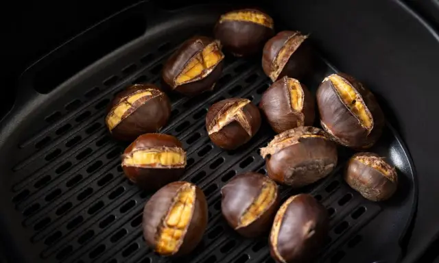 Castagne arrostite nella friggitrice ad aria, con la buccia aperta che rivela il loro interno dorato e invitante.