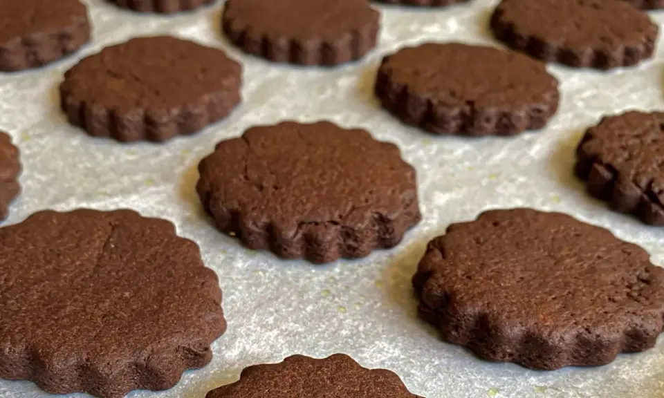 Deliziosi biscotti senza burro al cacao, con bordo ondulato, disposti su una teglia.