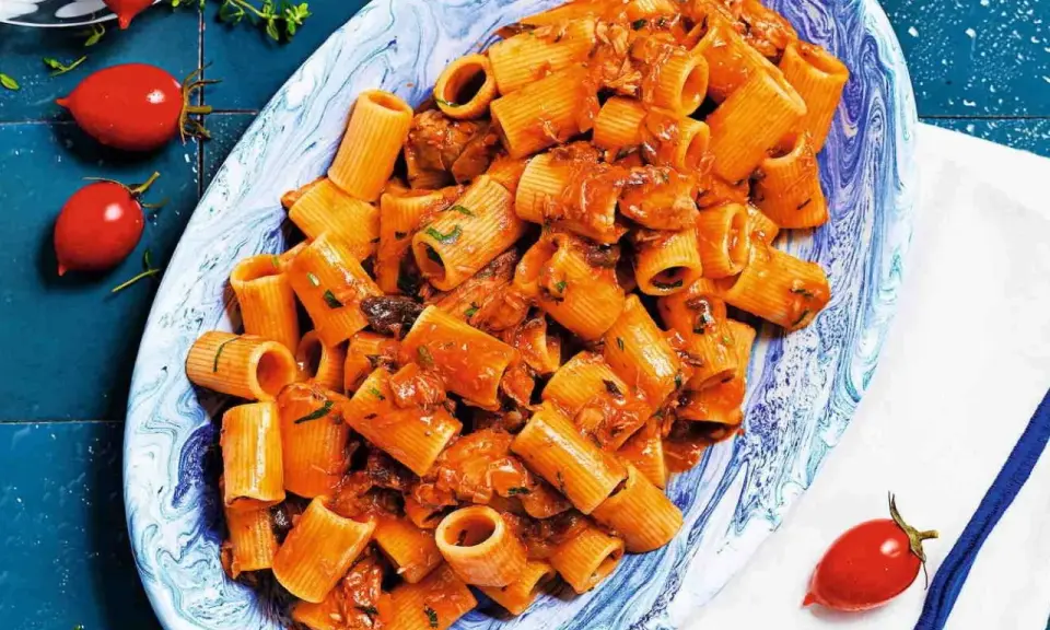 Rigatoni conditi con un sugo rosso saporito, ricco di tonno e erbe aromatiche. Un piatto di pasta al tonno invitante.
