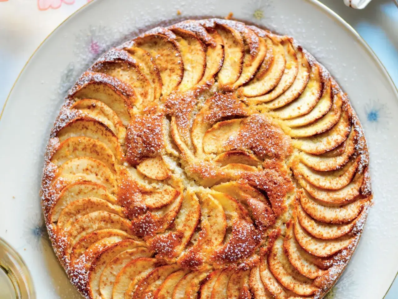 Una deliziosa torta di mele, con fette disposte a raggiera e una spolverata di zucchero a velo.