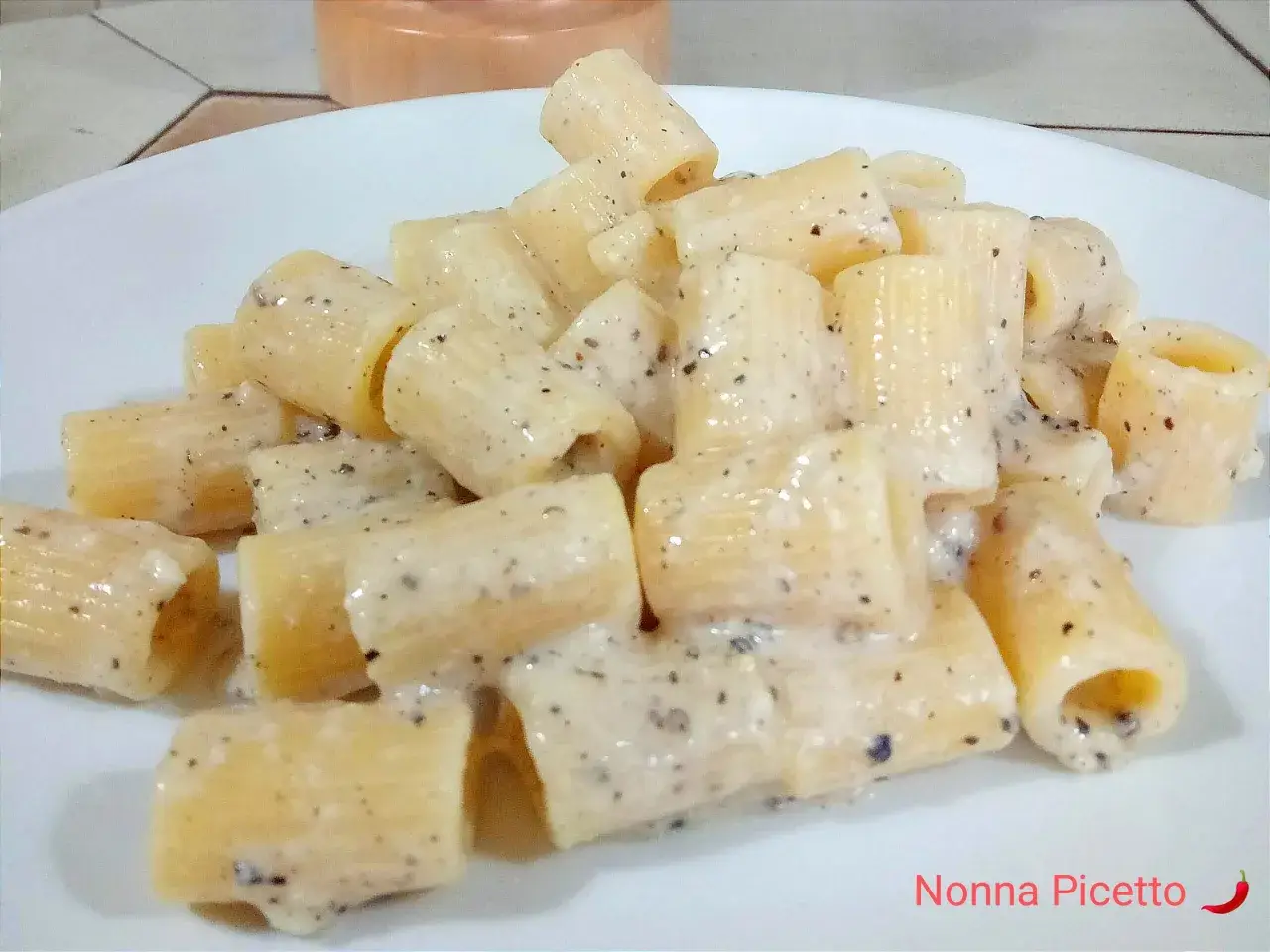Piatto di rigatoni cremosi conditi con un classico cacio e pepe, pronti per essere gustati.