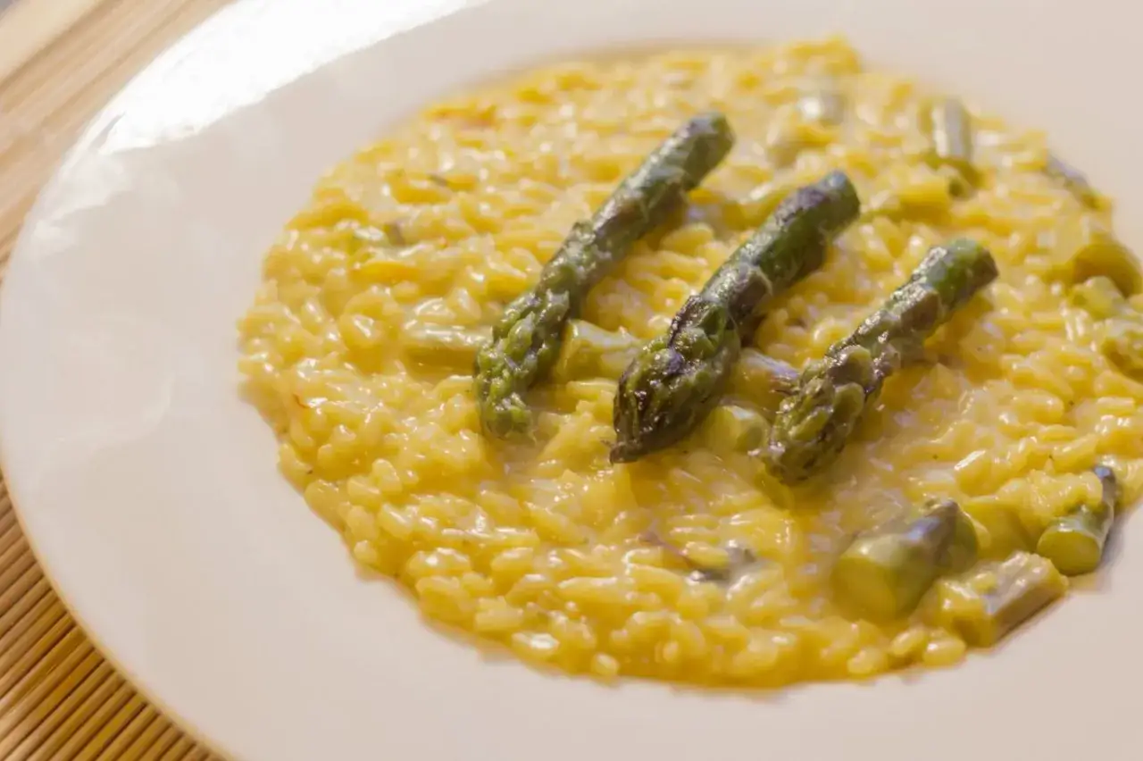 Un cremoso risotto asparagi e zafferano, guarnito con punte di asparagi freschi.