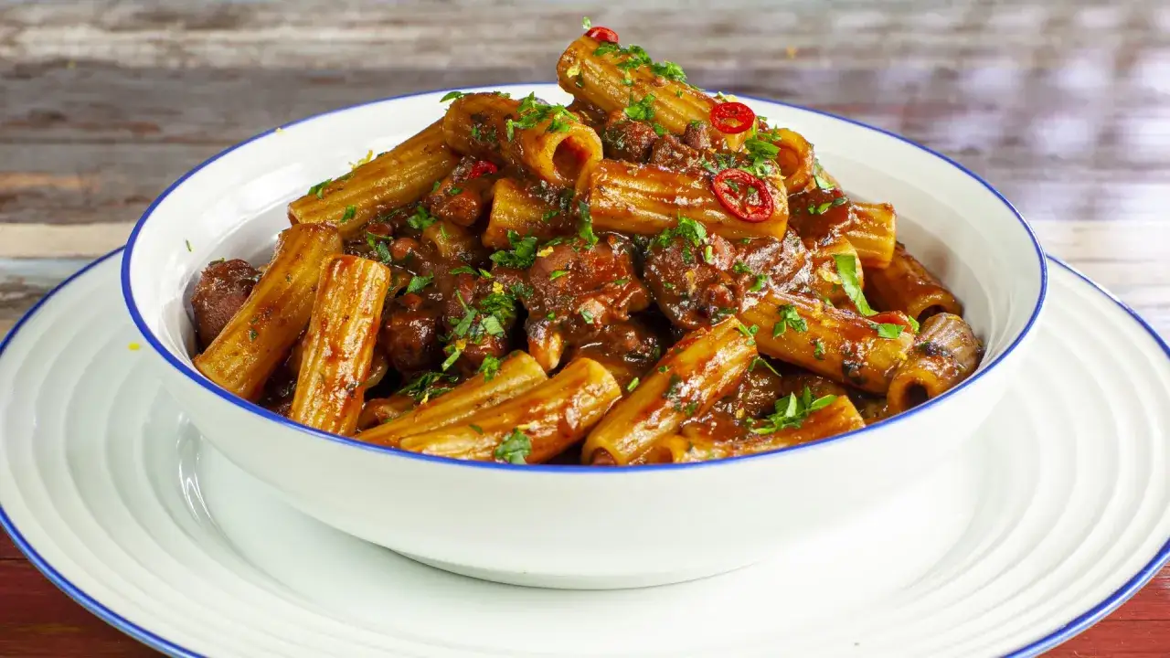 Rigatoni conditi con un saporito ragù di polpo, guarniti con prezzemolo fresco e peperoncino.