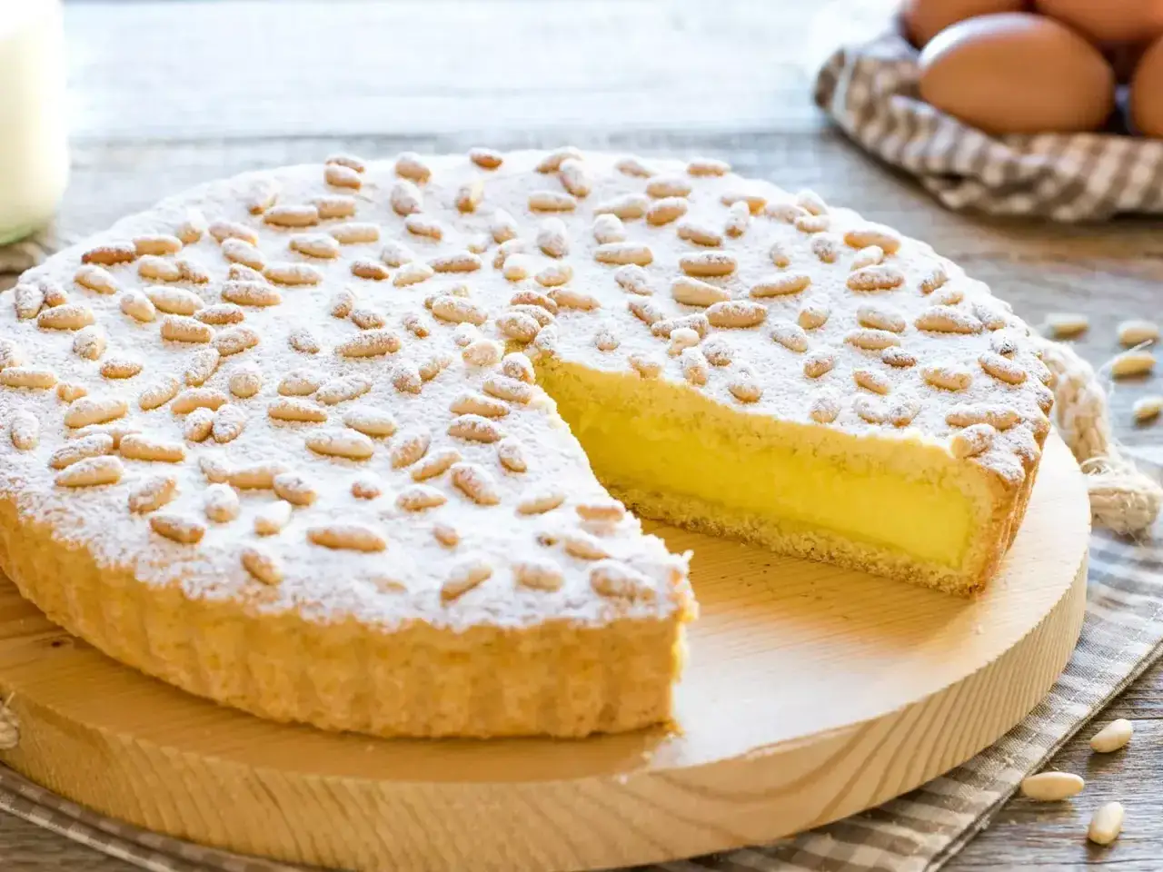 Una deliziosa torta della nonna, ricoperta di pinoli e zucchero a velo, con un ripieno cremoso e dorato.
