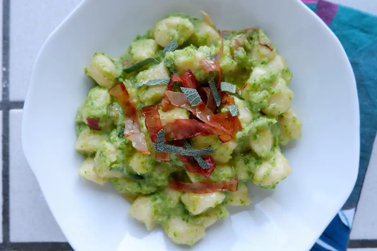 Gnocchi di zucchine cremosi, guarniti con prosciutto croccante e salvia fresca. Un piatto leggero e saporito.