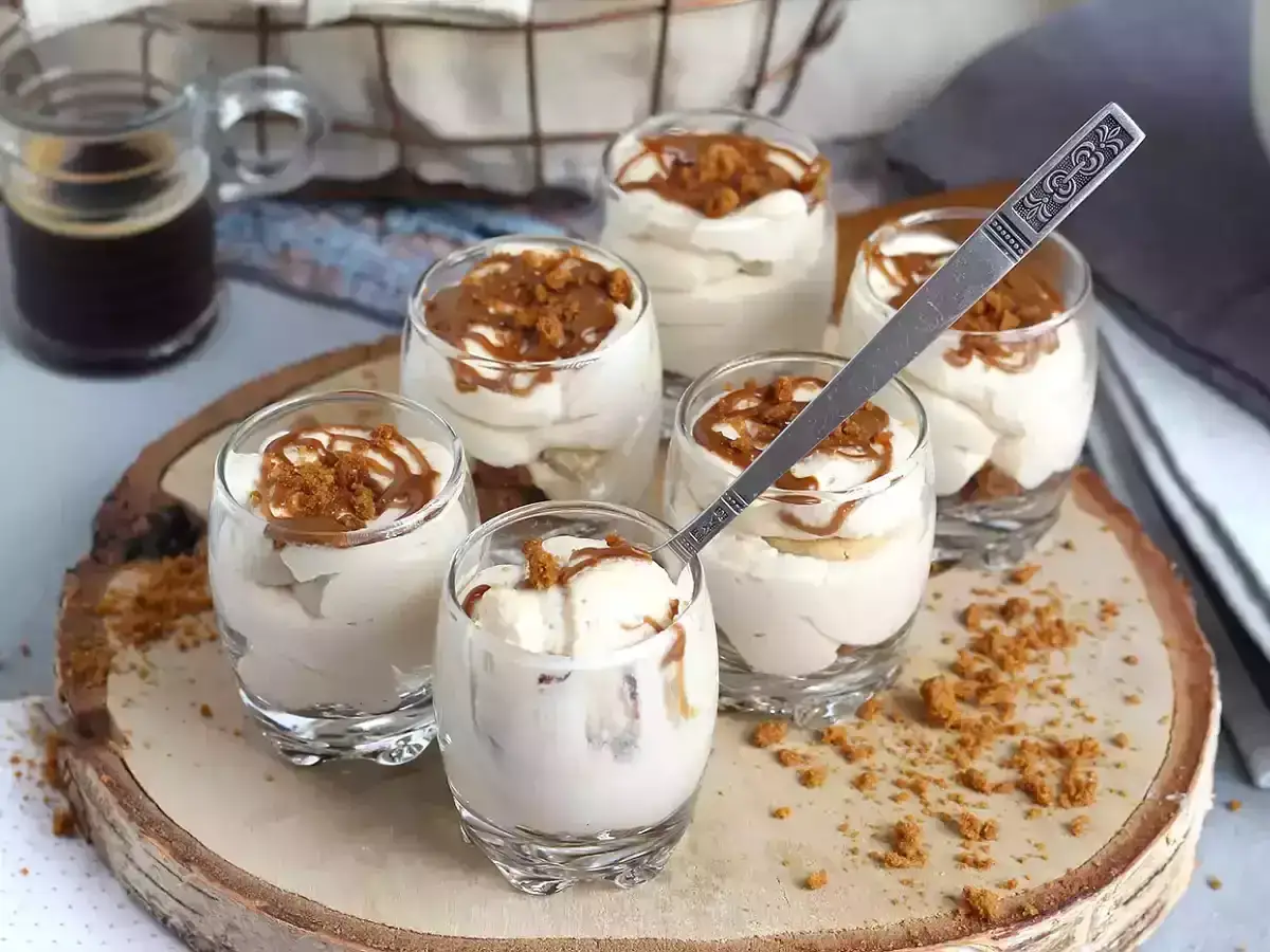 Deliziosi bicchierini con crema mascarpone e panna, guarniti con biscotti sbriciolati e caramello. Perfetti per un fine pasto goloso.