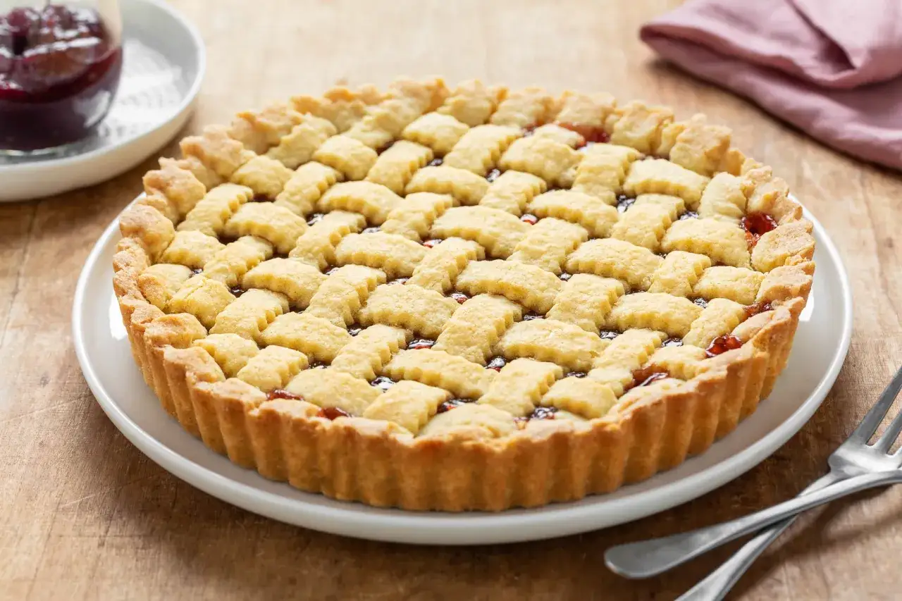 Una deliziosa crostata di marmellata con una griglia di pasta frolla dorata, pronta per essere gustata.