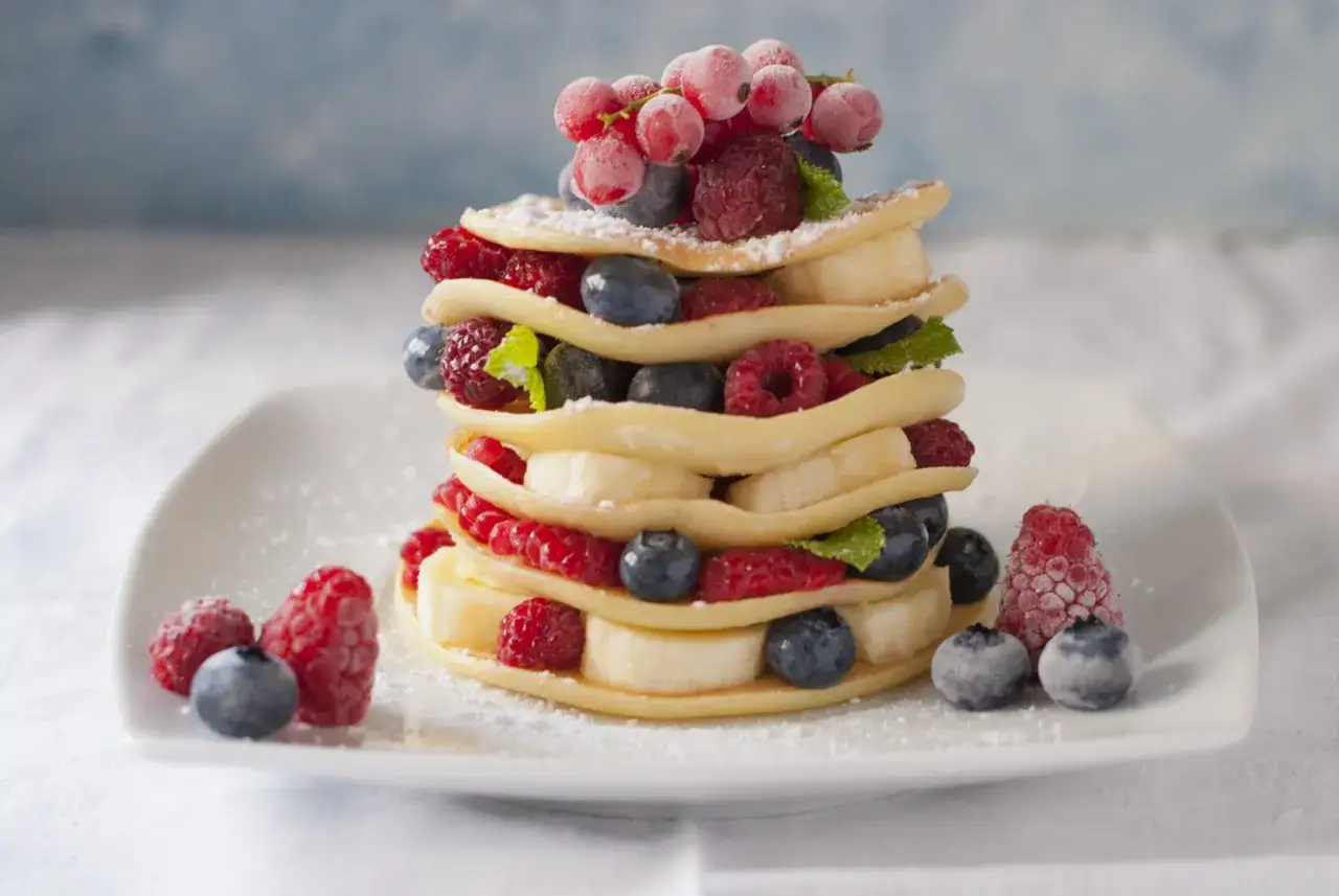 Torre di pancake senza glutine con lamponi, mirtilli, banana e ribes. Una delizia colorata e leggera.