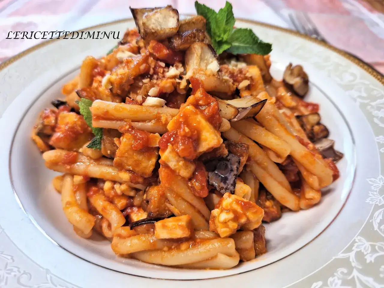 Pasta con pesce spada e melanzane, un piatto ricco e saporito, guarnito con menta fresca.