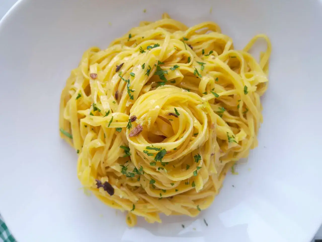 Un piatto di pasta burro e alici, condita con prezzemolo fresco e un tocco di limone.