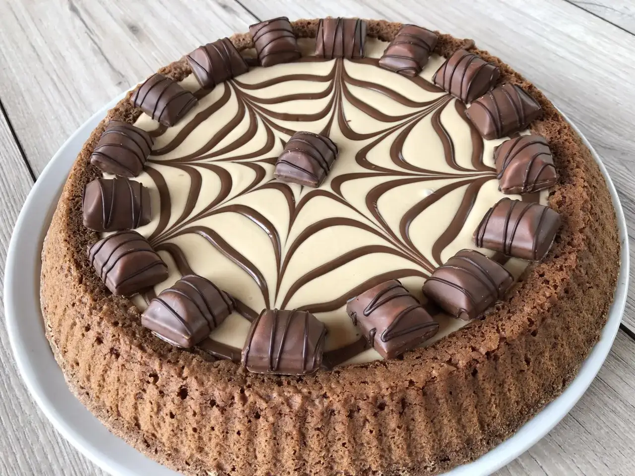 Torta Kinder Bueno con decorazione a ragnatela di cioccolato e panna, guarnita con pezzi di Kinder Bueno.