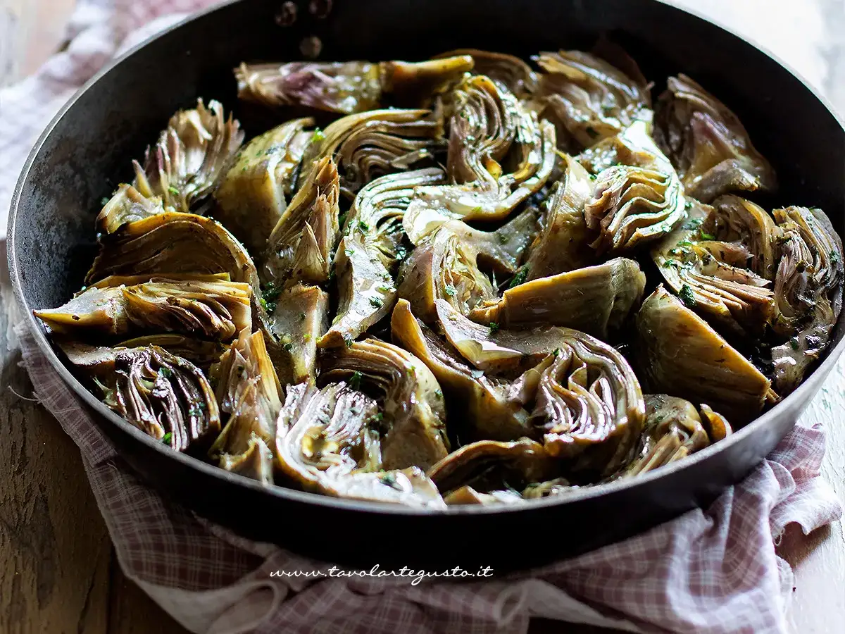 Carrellata di carciofi in padella, teneri e profumati, pronti per essere gustati.