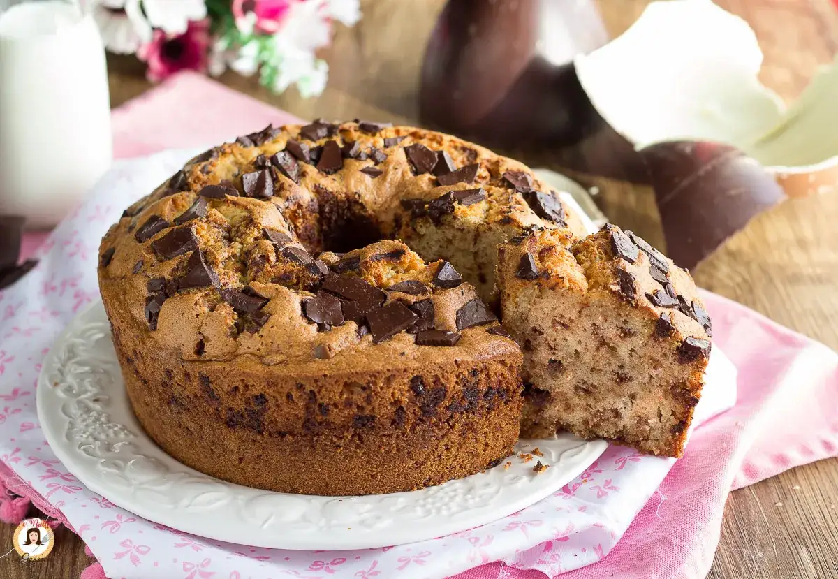 Ciambellone soffice con gocce di cioccolato, perfetto per Pasqua, con uova di cioccolato sullo sfondo.