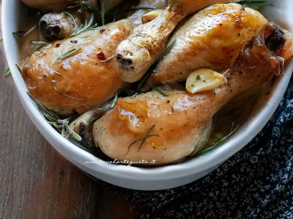 Sovracosce di pollo succulente, cotte con aglio e rosmarino in una ciotola bianca, pronte per essere gustate.
