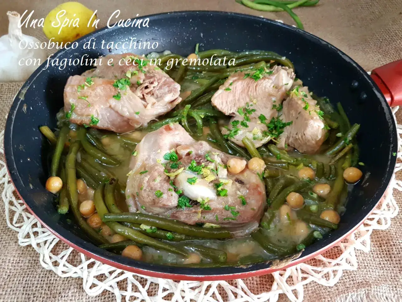 Ossobuco di tacchino cotto in padella con fagiolini e ceci, guarnito con prezzemolo tritato.