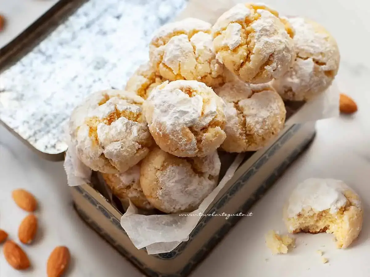 Biscotti con farina di mandorle, dolcemente spolverati di zucchero a velo, riposano in un contenitore vintage.