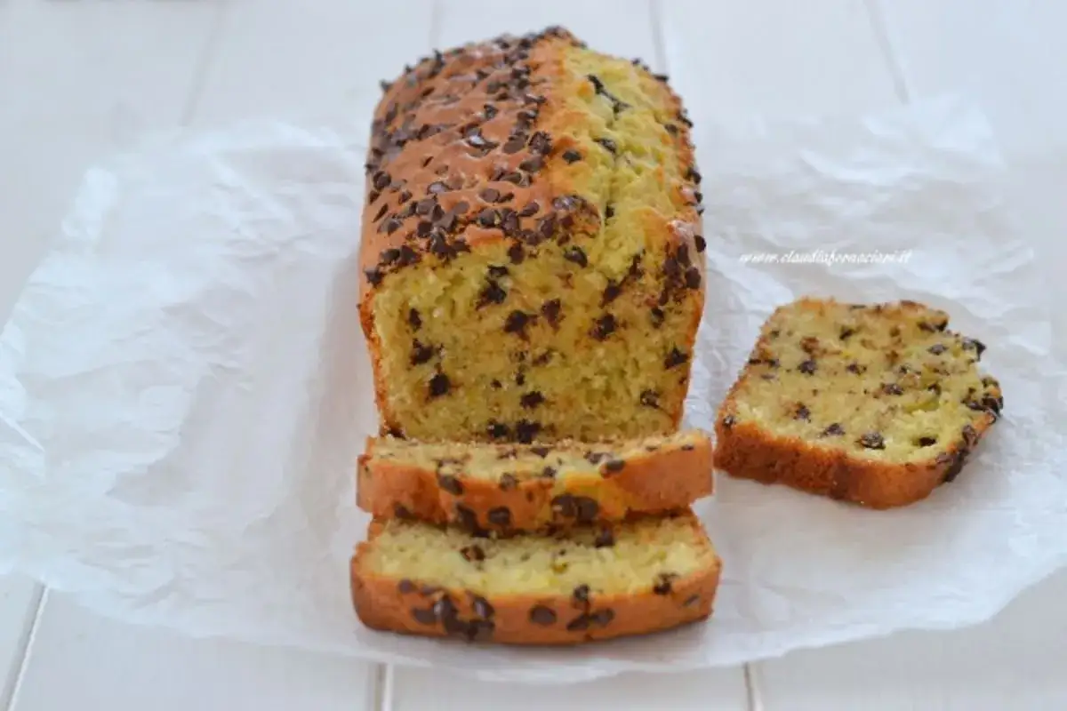 Plumcake con gocce di cioccolato, soffice e goloso, pronto per essere gustato. Una fetta tagliata mostra l'interno morbido e ricco di cioccolato.