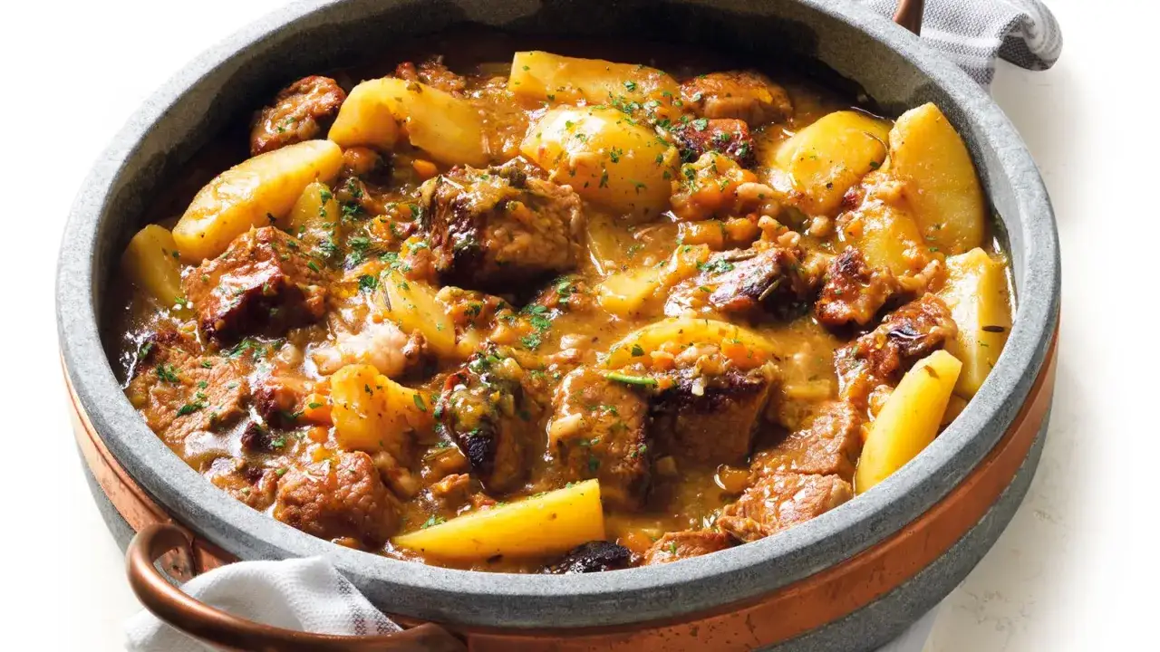 Un saporito spezzatino di manzo con patate, cotto lentamente in un tegame di pietra, guarnito con prezzemolo fresco.