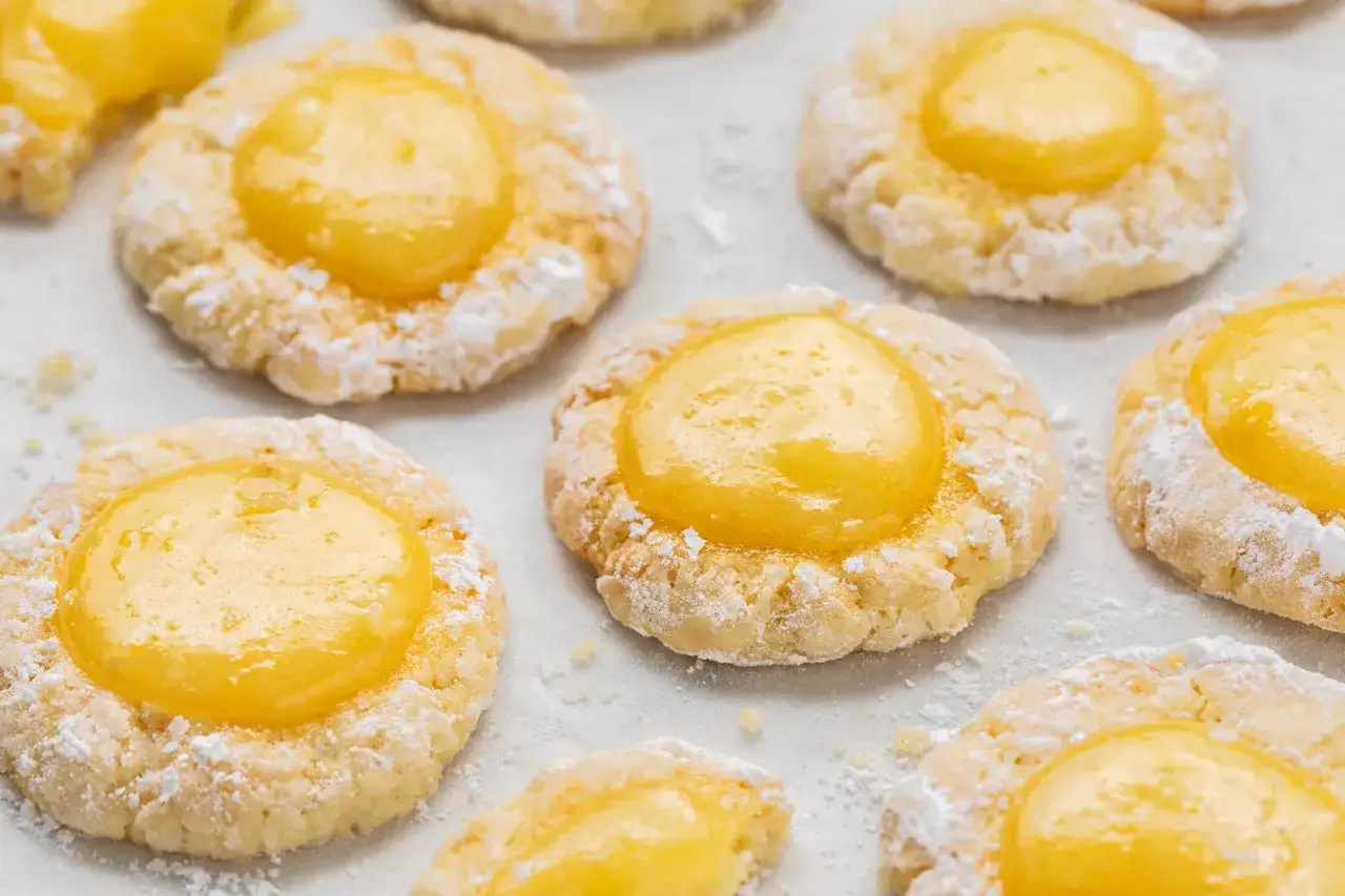 Biscotti friabili con un cuore di vibrante crema al limone, spolverati di zucchero a velo.
