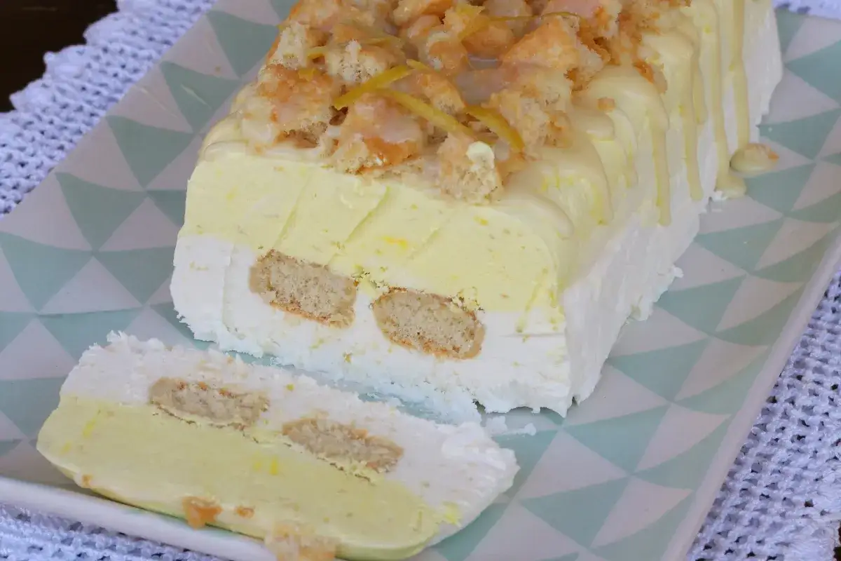 Delizioso semifreddo al limone a strati con biscotti, guarnito con briciole e scorzette.