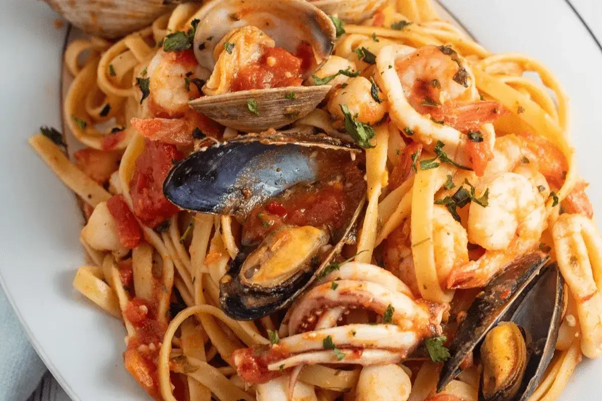 Un piatto invitante di scialatielli ai frutti di mare, con gamberi, cozze, vongole e calamari, conditi con pomodoro e prezzemolo.
