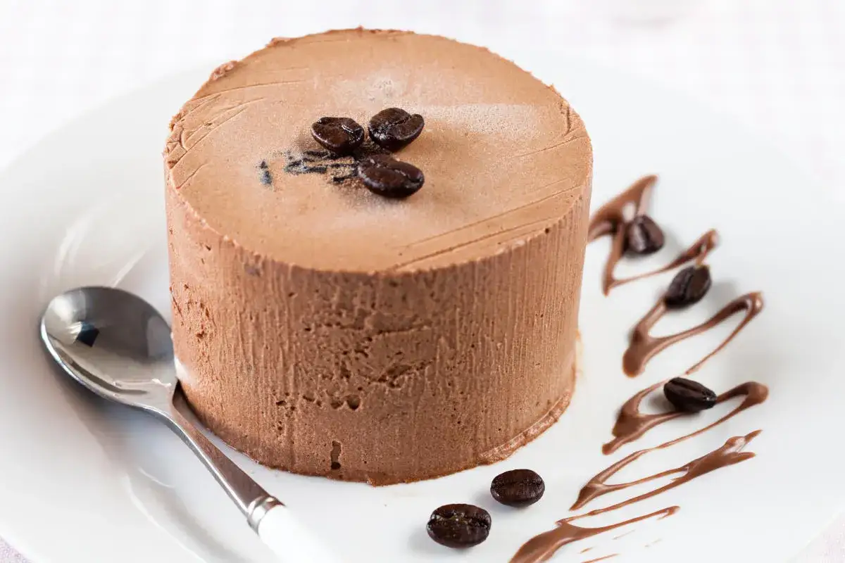 Delizioso semifreddo al caff&egrave;, guarnito con chicchi di caff&egrave; e un filo di cioccolato, pronto per essere gustato con un cucchiaino.