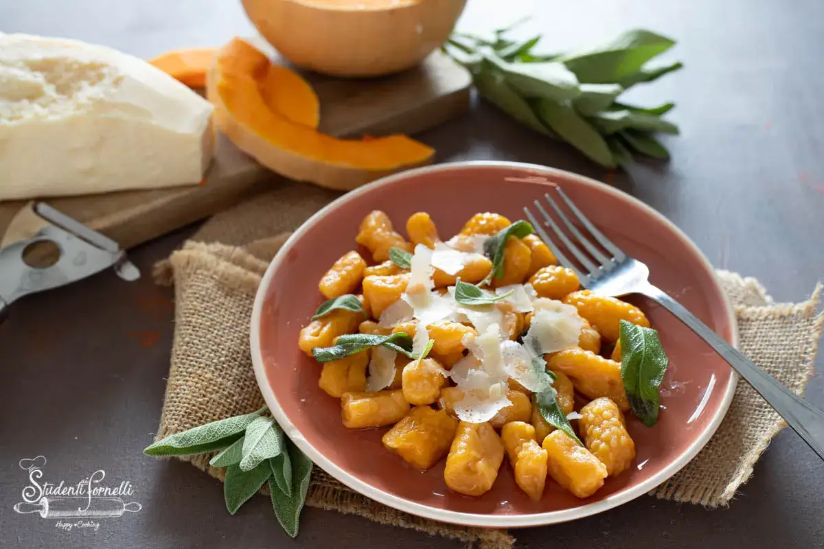 Gnocchi di zucca fatti in casa, conditi con salvia e parmigiano, pronti per essere gustati.