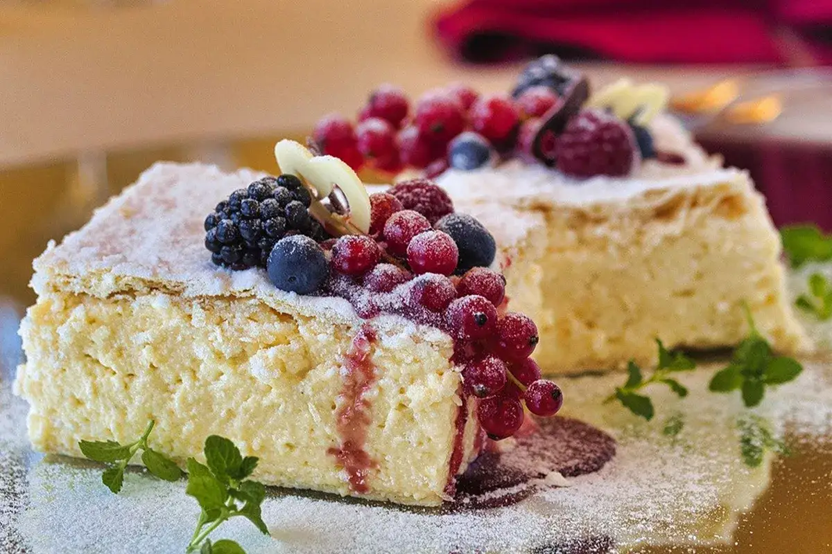 Fetta di torta al mascarpone con frutti di bosco freschi e una spolverata di zucchero a velo.