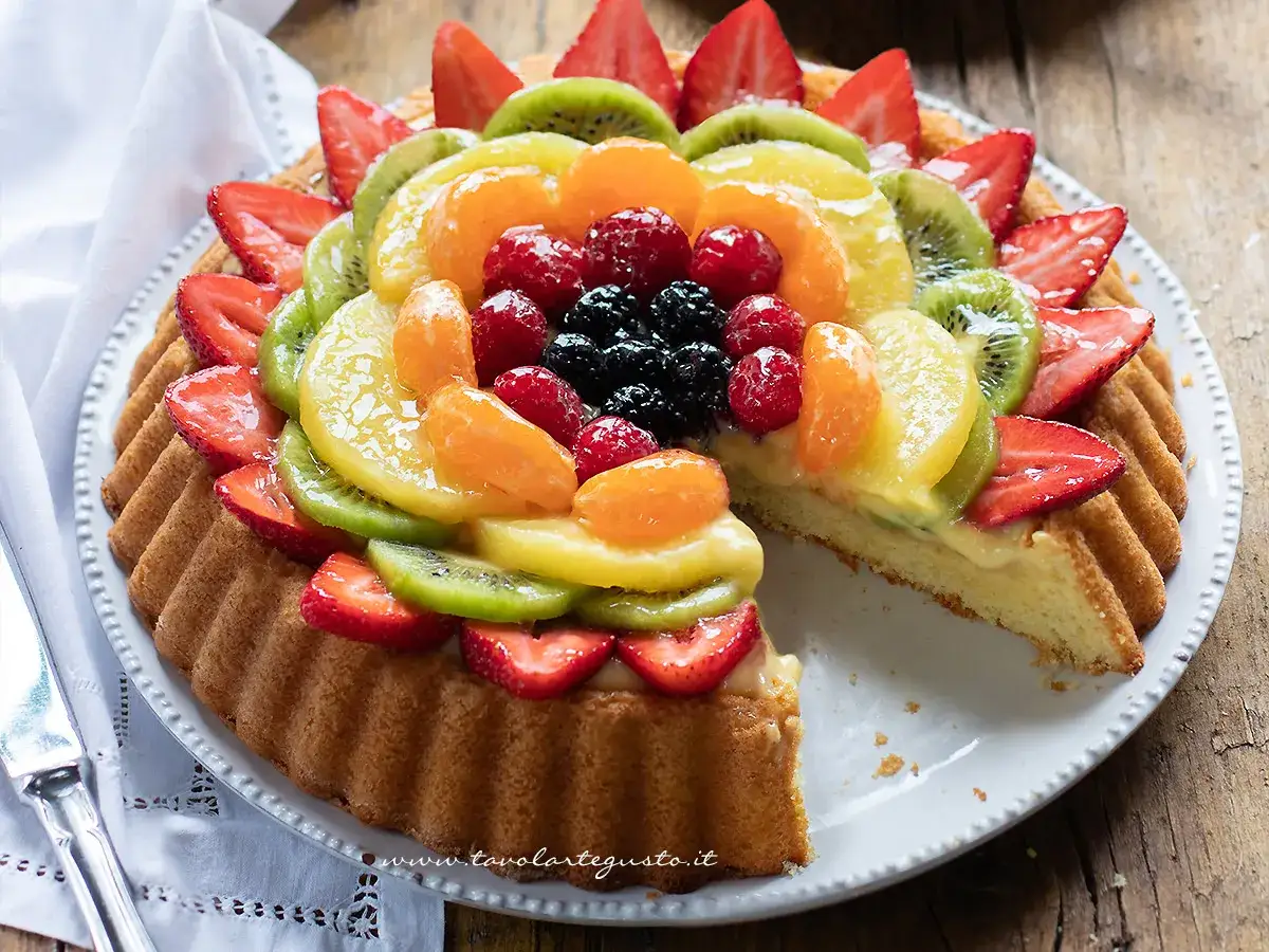 Una deliziosa torta alla frutta, con fragole, kiwi, mandarini e frutti di bosco, su una base di crema pasticcera.