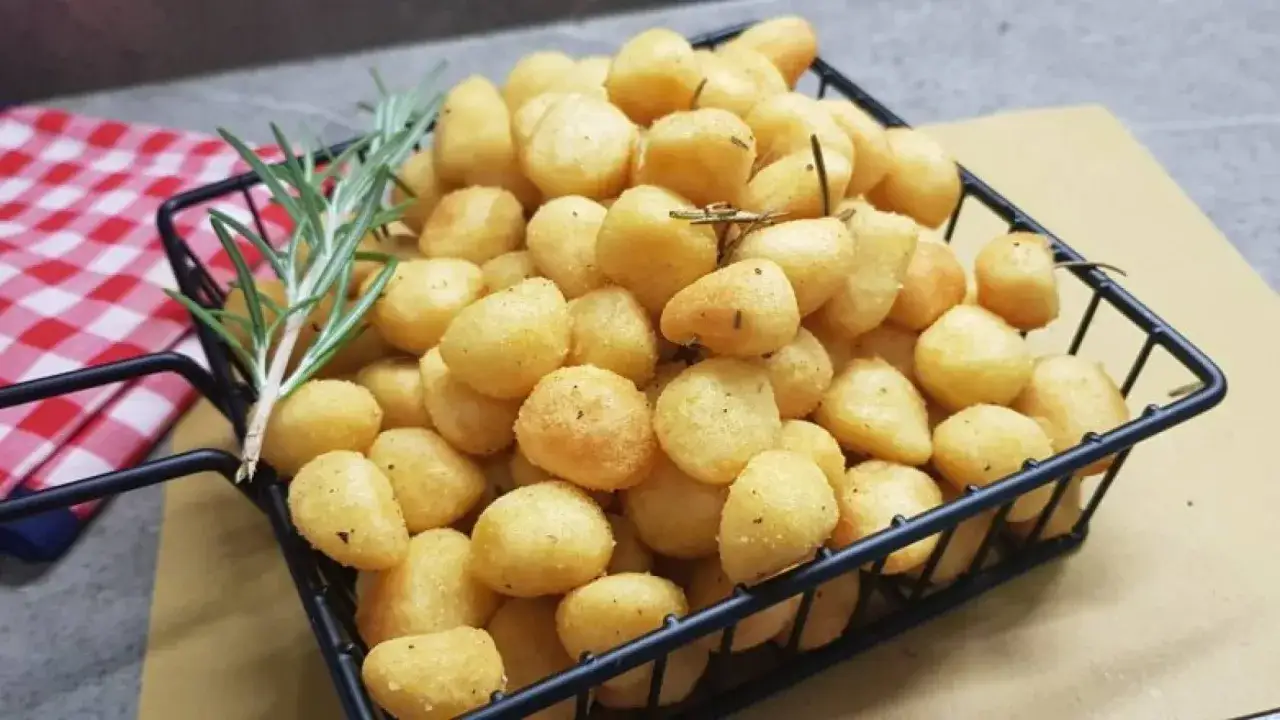 Gnocchi dorati e croccanti, cotti nella friggitrice ad aria, serviti in un cestino con rosmarino.