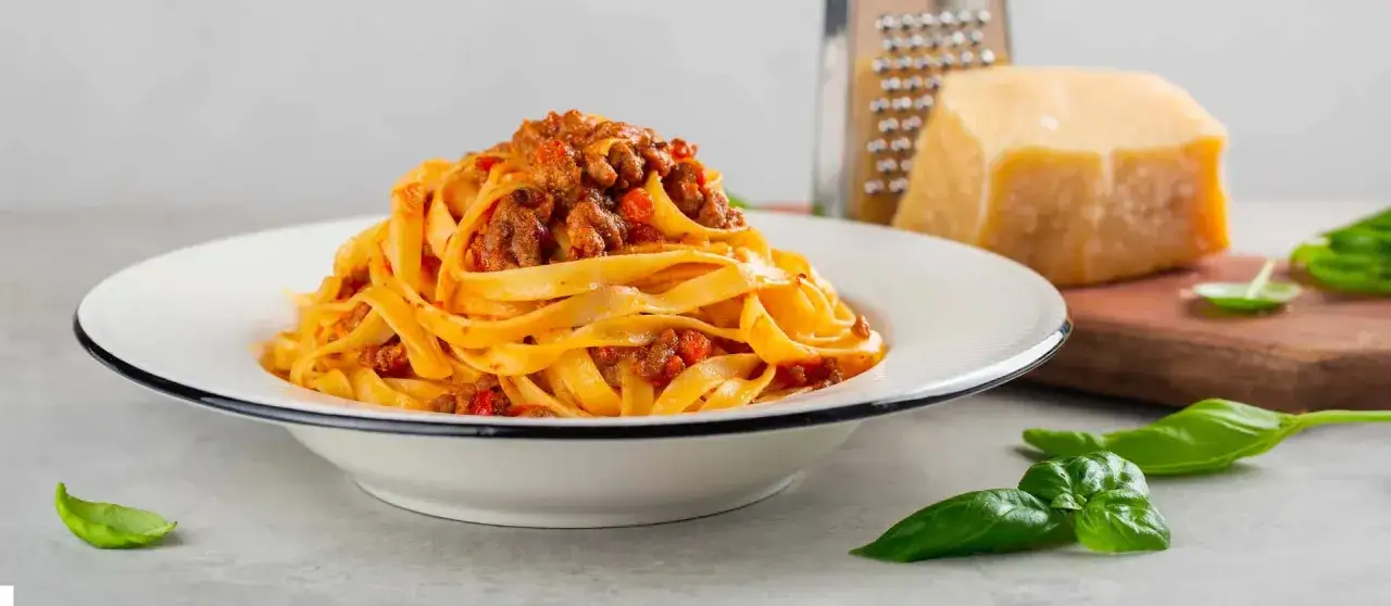 Tagliatelle al ragù, un classico dei primi piatti della domenica, con parmigiano e basilico fresco.