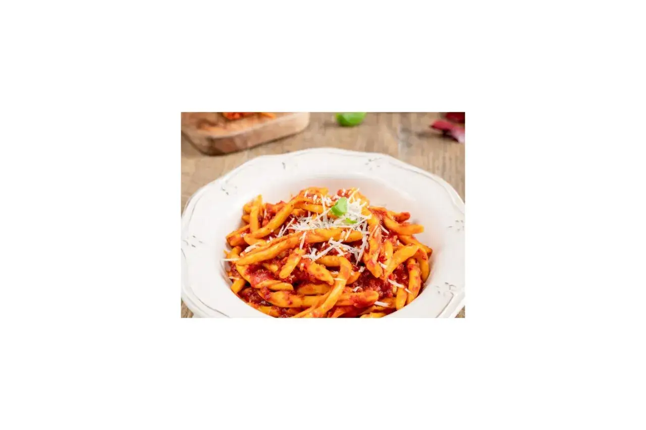 Piatto di pasta con sugo rosso piccante e formaggio grattugiato, un classico della cucina italiana: pasta con nduja.
