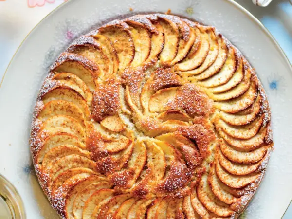 Una deliziosa torta di mele, con fette disposte a raggiera e una spolverata di zucchero a velo.