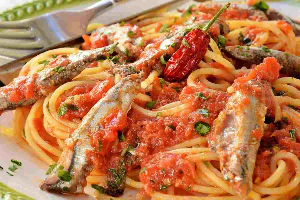 Spaghetti con sugo di pomodoro, acciughe intere e un peperoncino rosso piccante. Un piatto di pasta semplice e saporito.